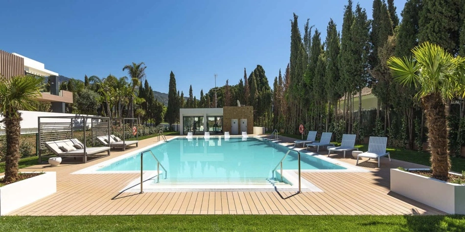 La zone de la piscine d'un autre point de vue. Chaises longues, herbe et eau cristalline